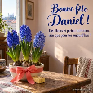 Trois jacinthes bleues de fleuriste fleurissent dans une coupe blanche entourée d’un ruban corail. Le message est : « Bonne fête Daniel ! Des fleurs et plein d’affection, rien que pour toi aujourd’hui ! ».