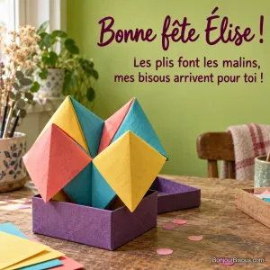 Une énorme cocotte en papier multicolore déborde comiquement d’une minuscule boîte cadeau ouverte. Le message est : « Bonne fête Élise ! Les plis font les malins, mes bisous arrivent pour toi ! ».