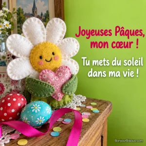 Une grande marguerite en tissu présente un cœur rose, parmi des décorations de Pâques colorées, avec le texte « Joyeuses Pâques, mon cœur ! Tu mets du soleil dans ma vie ! ».